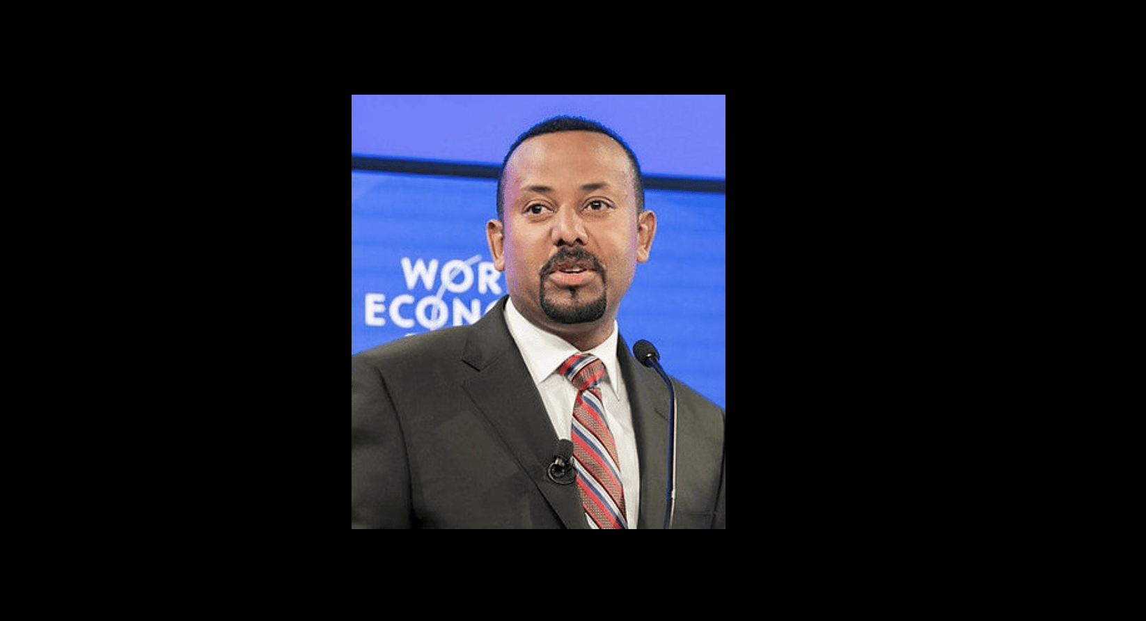 Ethiopian Prime Minister Abiy Ahmed in front of blue background, with words "World Economic Forum" in white.